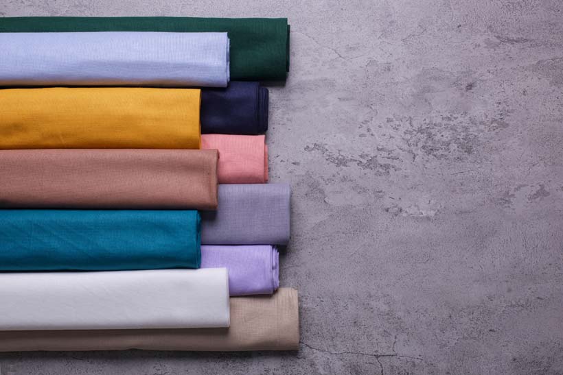 top-view-various-rolled-up-colorful-ceruty-fabric-isolated-cement-background-with-copy-space.jpg
