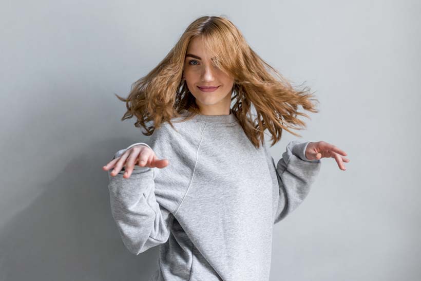 smiling-blonde-young-woman-dancing-against-grey-wall_1.jpg